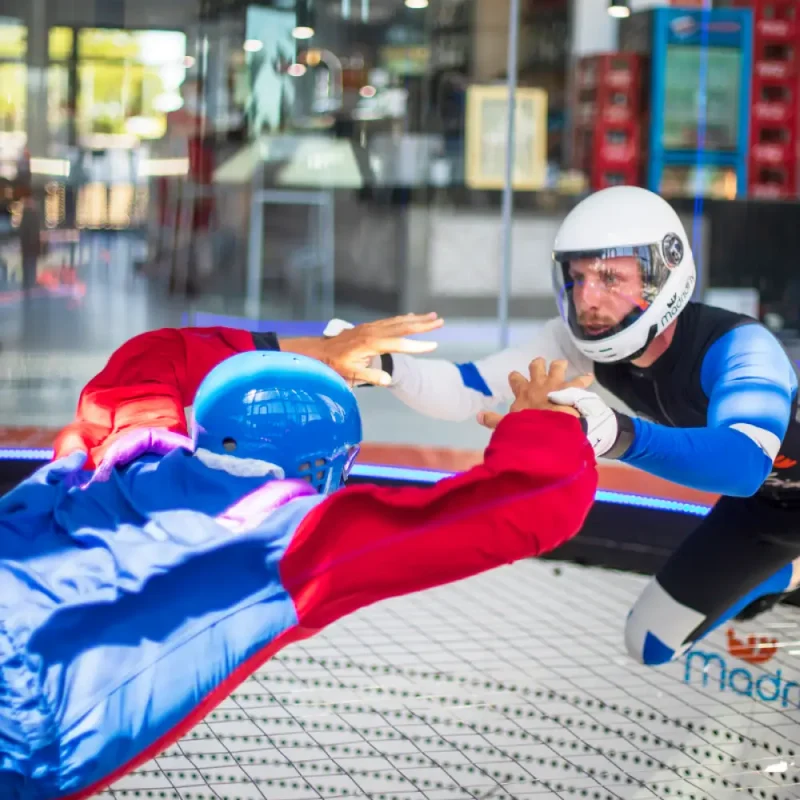 Instructor de vuelo sosteniendo las manos a persona volando en el túnel de viento